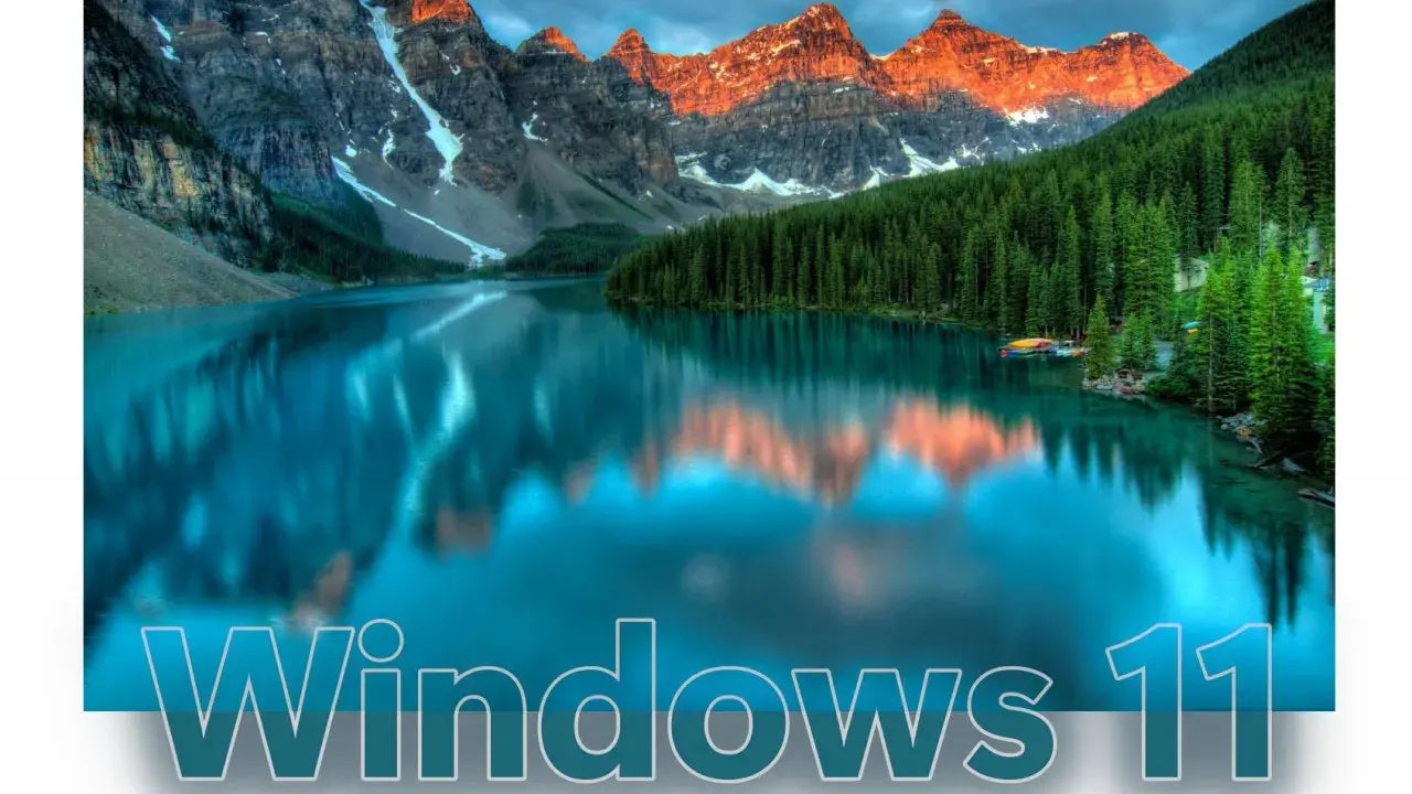 Bergsee mit Spiegelung, Wald und dem Schriftzug "Windows 11". Ein visueller Unterschied zu Windows 10.
