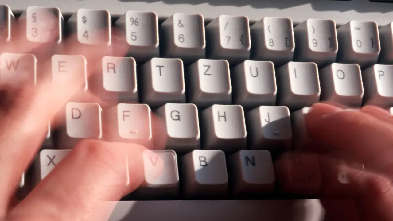 Hände tippen schnell auf einer Tastatur. Vielleicht wird gerade ein Befehl wie "diskpart delete partition" eingegeben.