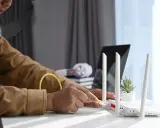 Mann schließt ein Netzwerkkabel an einen Router an, um seinen Laptop als Router zu verwenden.
