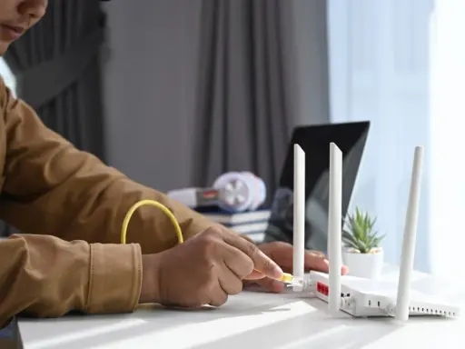 Mann schließt ein Netzwerkkabel an einen Router an, um seinen Laptop als Router zu verwenden.