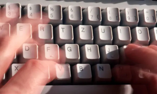 Hände tippen schnell auf einer Tastatur. Vielleicht wird gerade ein Befehl wie "diskpart delete partition" eingegeben.