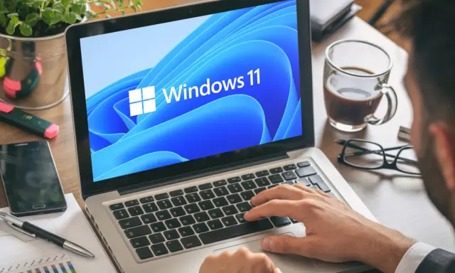 Mann tippt auf Laptop mit Windows 11. Ein netspeedmonitor könnte hier nützlich sein, um die Leistung zu prüfen.